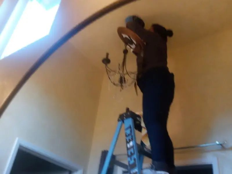Electrician installing a chandelier in a Marble Falls residence